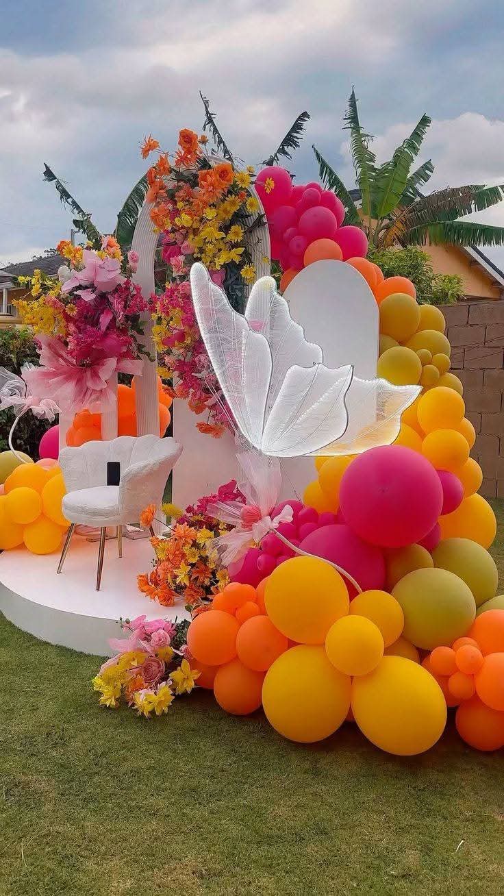 Outdoor garden birthday decoration in Lagos — butterfly backdrop with pink, orange and yellow balloon garland by Ma'jestik Events